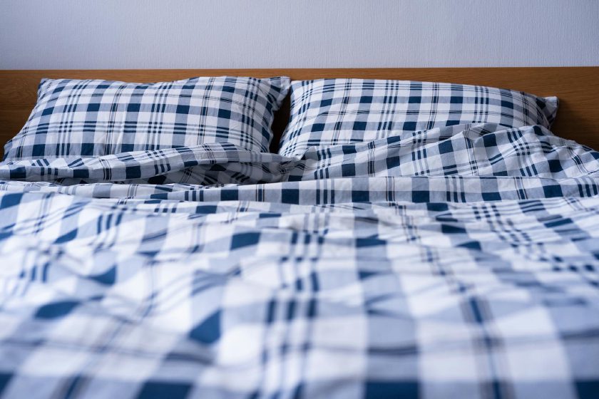 Weich gefaltete weiße und blaue Bettwäsche im Tageslicht